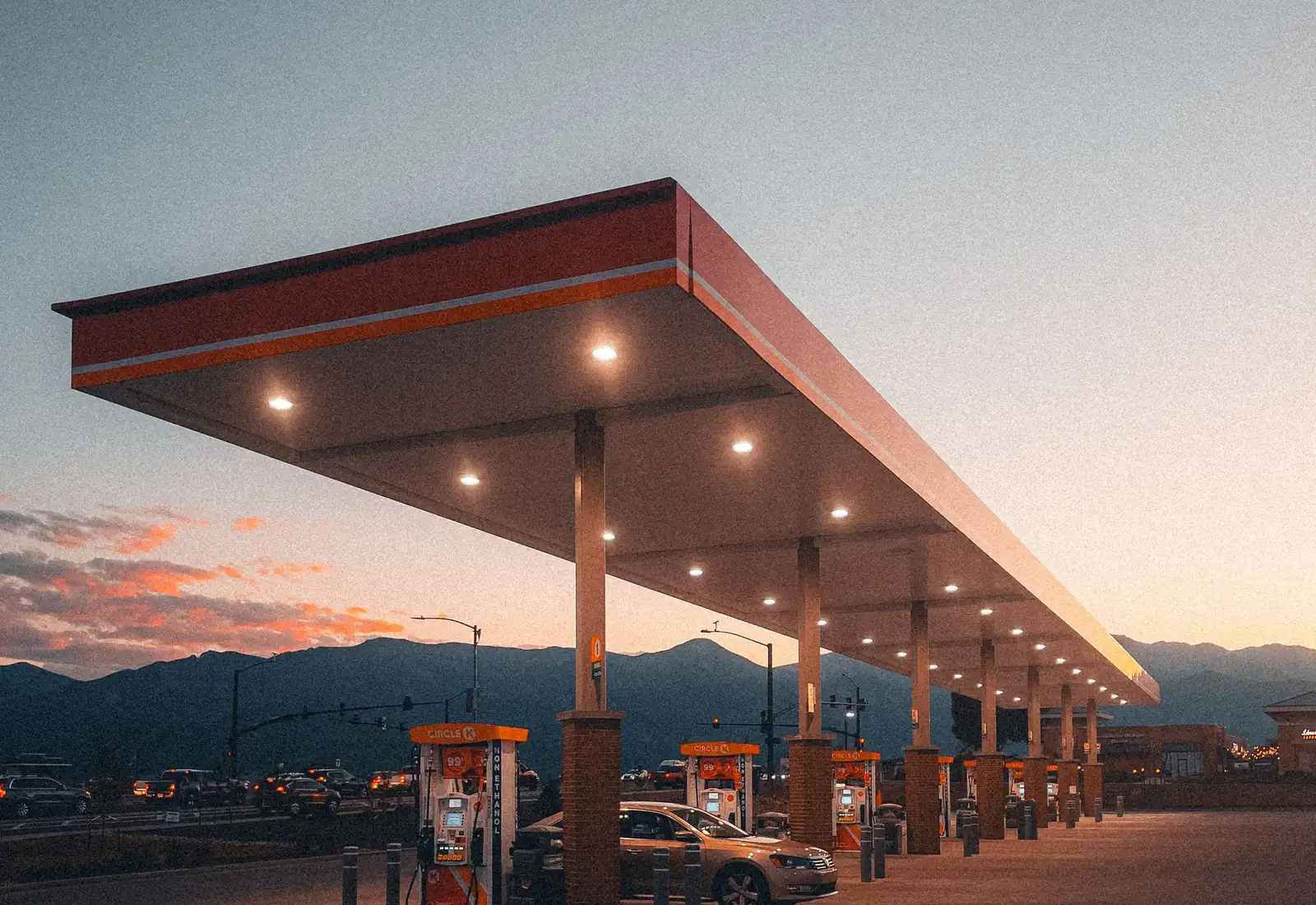 Fuel pumps under a station canopy at dusk